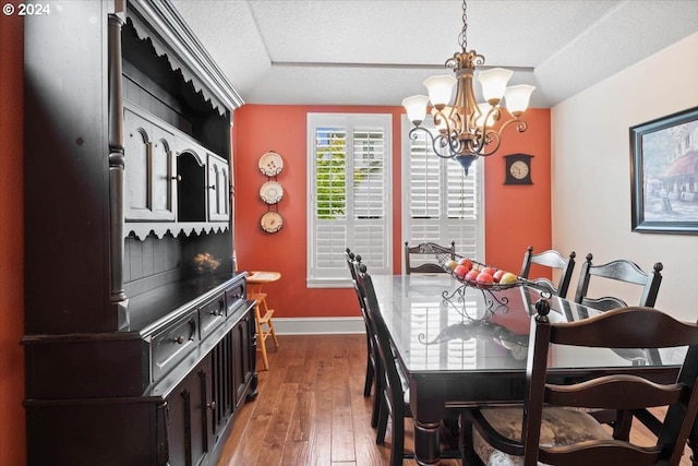 dining space featuring hardwood / wood-style flooring, a textured ceiling, and a chandelier