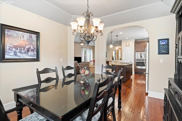 dining space with dark wood-type flooring, a tray ceiling, and an inviting chandelier