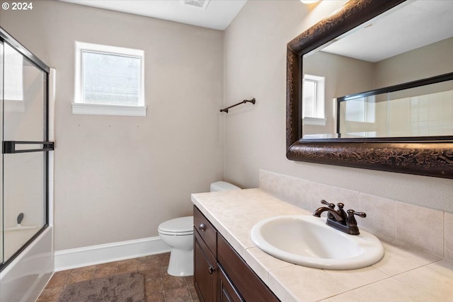 full bathroom with combined bath / shower with glass door, toilet, and vanity