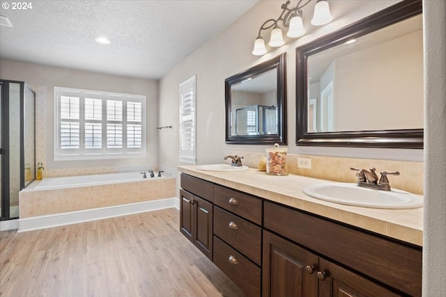 bathroom with vanity, wood-type flooring, a textured ceiling, and independent shower and bath