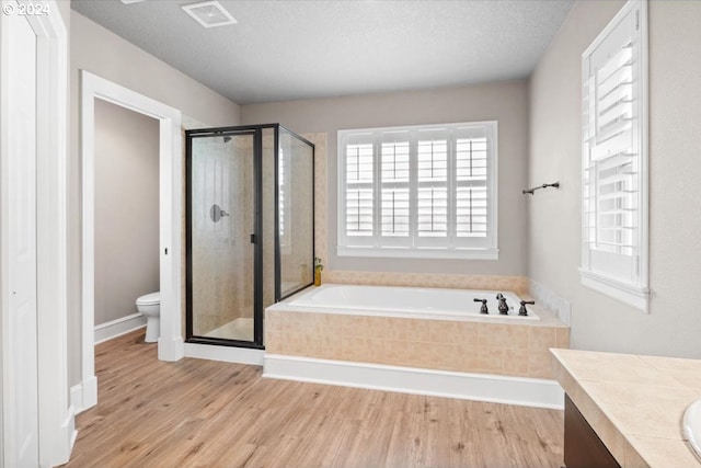 full bathroom featuring vanity, separate shower and tub, toilet, and a textured ceiling