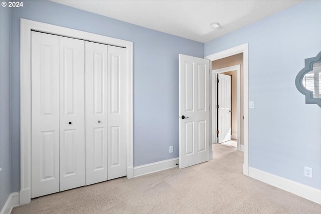 unfurnished bedroom with light carpet and a closet