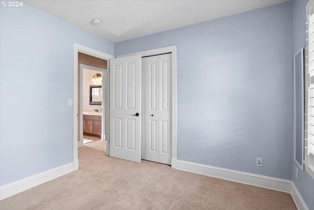 unfurnished bedroom with light carpet, a closet, and sink