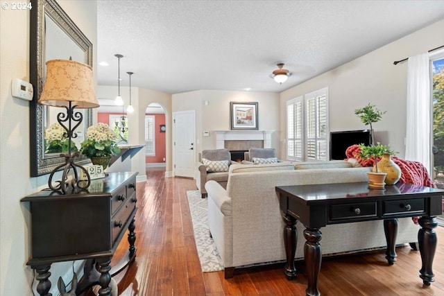 living room with a tiled fireplace, a textured ceiling, and hardwood / wood-style flooring