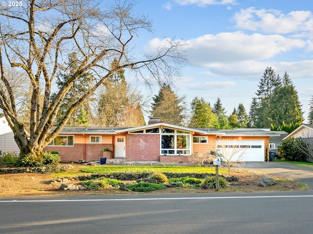 view of front facade featuring brick siding, a chimney, concrete driveway, and an attached garage