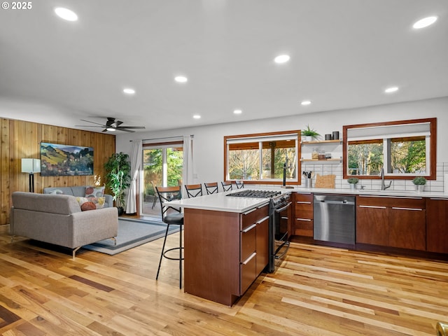 kitchen with appliances with stainless steel finishes, light countertops, a kitchen breakfast bar, and a sink