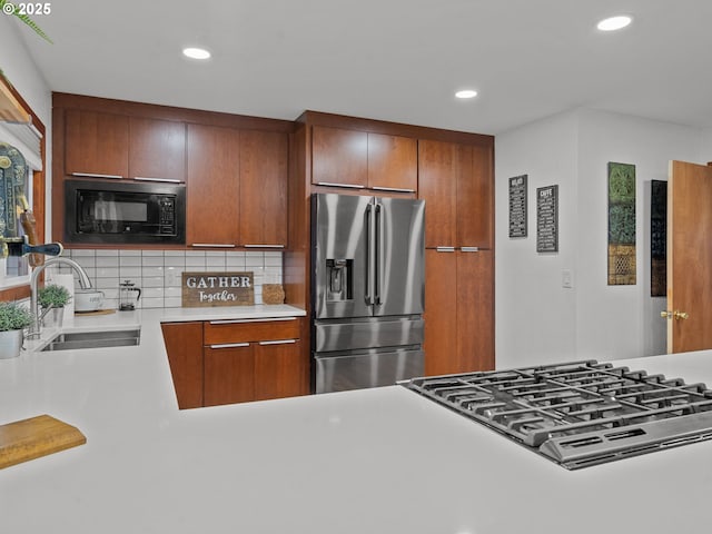 kitchen with stovetop, stainless steel fridge with ice dispenser, a sink, light countertops, and black microwave