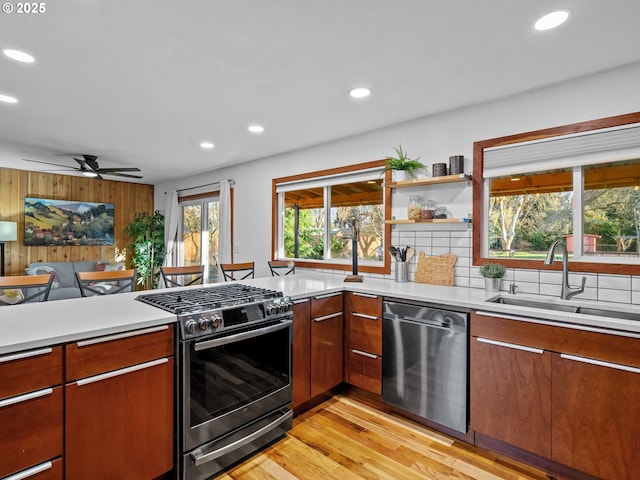 kitchen with a sink, appliances with stainless steel finishes, open floor plan, and light countertops