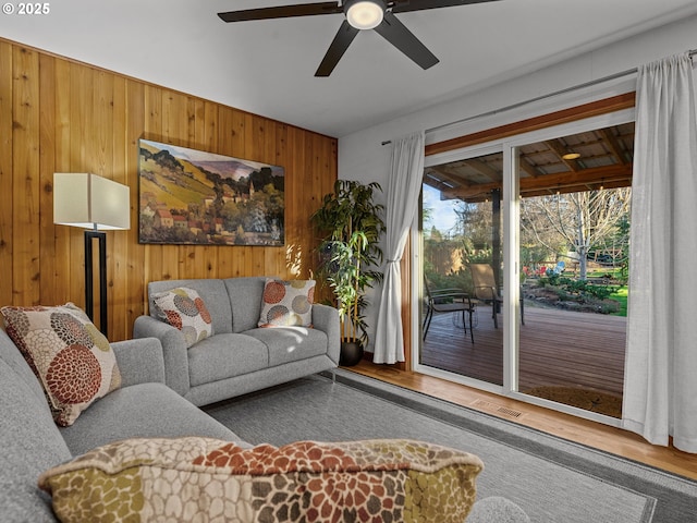 living room with visible vents, wood walls, and wood finished floors