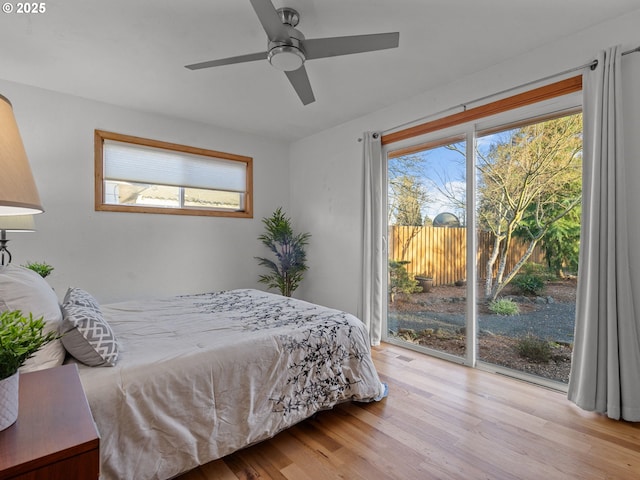 bedroom featuring a ceiling fan, access to exterior, multiple windows, and wood finished floors