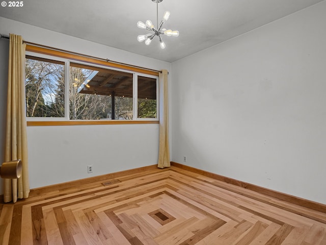 empty room featuring visible vents, baseboards, and an inviting chandelier