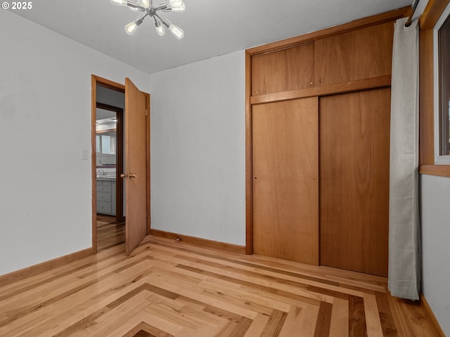 unfurnished bedroom with a notable chandelier, baseboards, a closet, and a sink