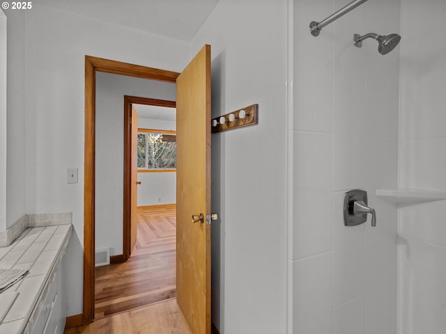 full bath with wood finished floors, a shower, and visible vents