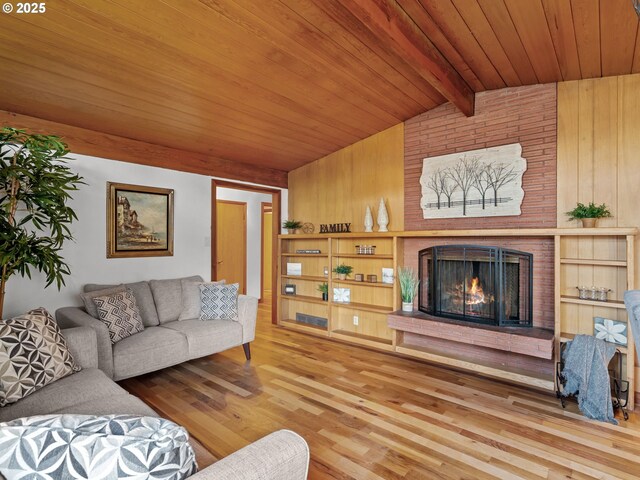 living room with lofted ceiling with beams, wood finished floors, wooden walls, a brick fireplace, and wood ceiling