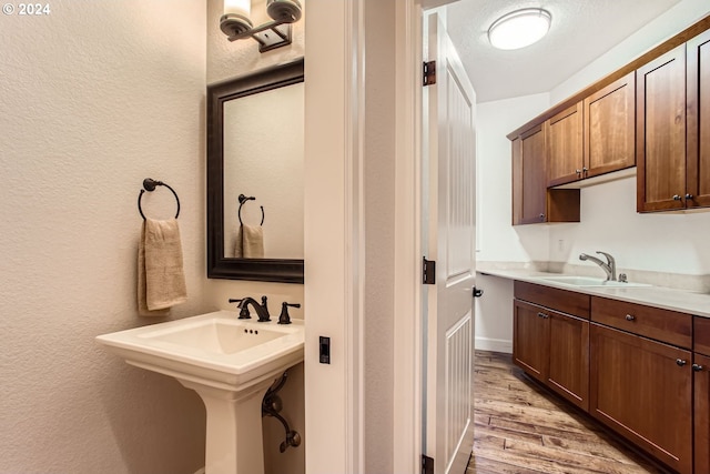 bathroom with a textured ceiling, wood-type flooring, and sink