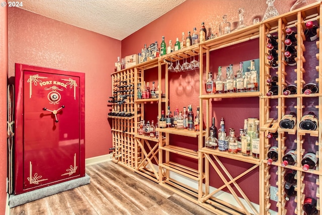 wine cellar with wood-type flooring and a textured ceiling