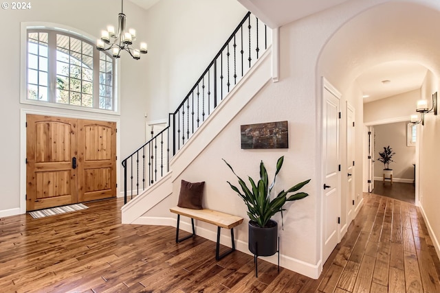 foyer featuring a notable chandelier, a towering ceiling, and dark wood-type flooring