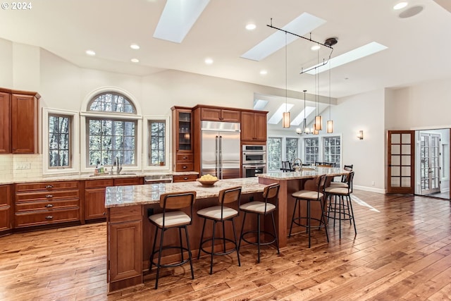 13516 NW Glendoveer Dr, Portland, OR 97231 - kitchen with appliances with stainless steel finishes, a skylight, high vaulted ceiling, a sink, and light wood finished floors