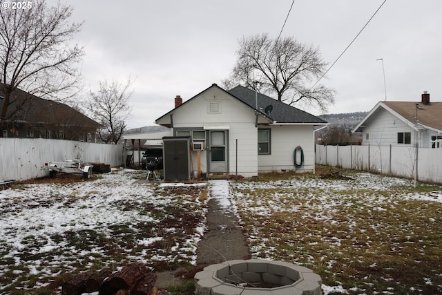 snow covered rear of property featuring cooling unit and an outdoor fire pit