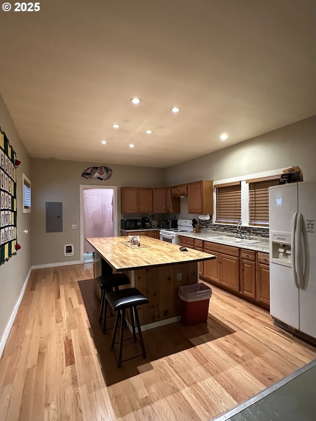 kitchen with white appliances, sink, light hardwood / wood-style flooring, butcher block countertops, and a kitchen island