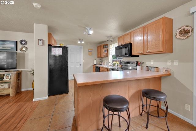 87973 Sherwood St, Veneta, OR 97487 - kitchen with black appliances, a peninsula, baseboards, and light countertops