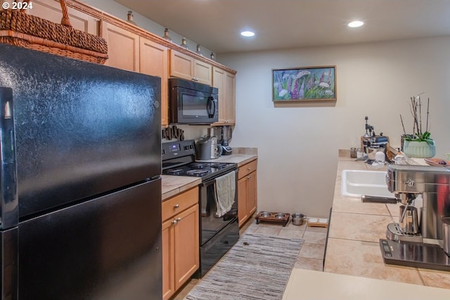 kitchen featuring black appliances, light brown cabinets, and tile counters