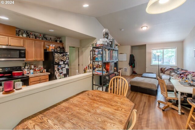 interior space with black refrigerator, light hardwood / wood-style flooring, vaulted ceiling, and electric range