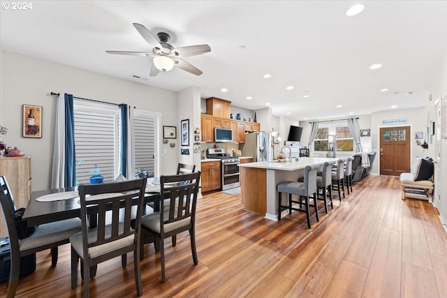 dining space featuring light hardwood / wood-style floors, ceiling fan, and sink