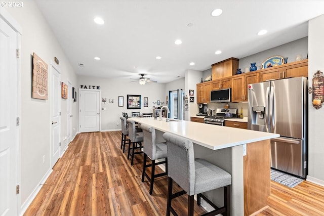 kitchen featuring stainless steel appliances, hardwood / wood-style flooring, an island with sink, and a breakfast bar area