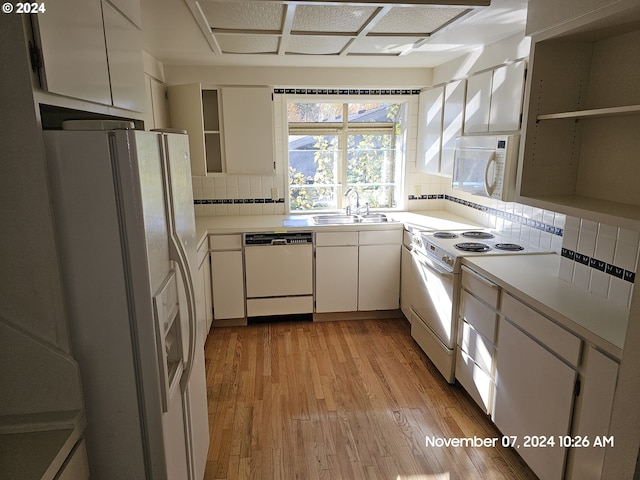 kitchen with sink, light hardwood / wood-style floors, white appliances, decorative backsplash, and white cabinets