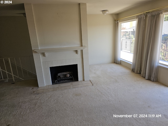 unfurnished living room with a healthy amount of sunlight, light colored carpet, and a fireplace