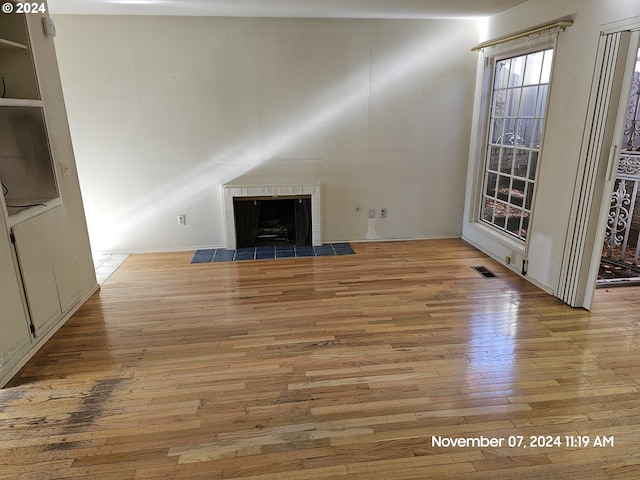 unfurnished living room featuring a brick fireplace and light hardwood / wood-style flooring