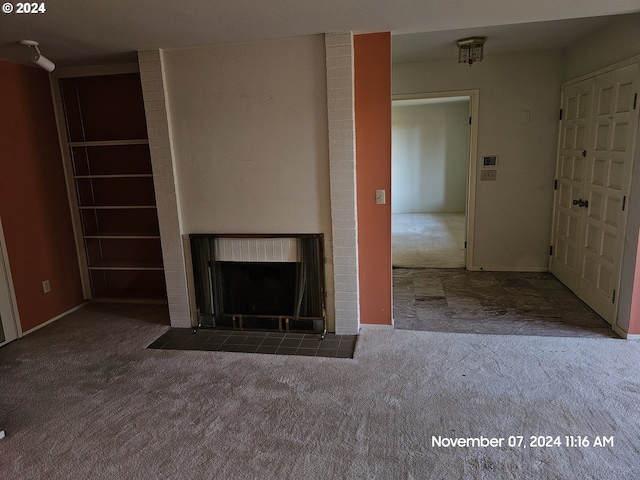 unfurnished living room featuring a brick fireplace and dark colored carpet