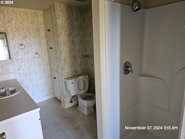 bathroom with tile patterned flooring, vanity, toilet, and a shower