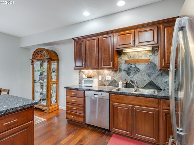 kitchen with tasteful backsplash, dark stone counters, stainless steel appliances, sink, and dark hardwood / wood-style floors