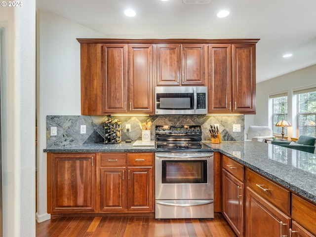 kitchen featuring decorative backsplash, stainless steel appliances, light hardwood / wood-style flooring, and dark stone counters