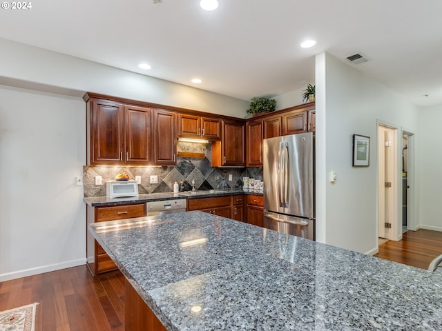 kitchen with decorative backsplash, stainless steel appliances, dark hardwood / wood-style floors, and dark stone counters