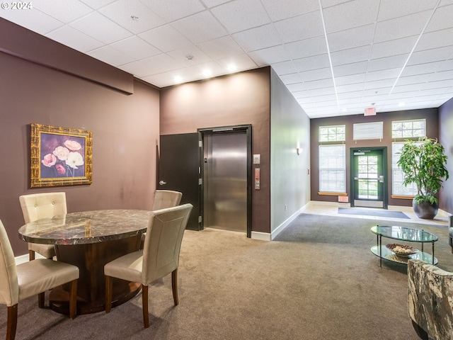 carpeted dining space with elevator and a drop ceiling