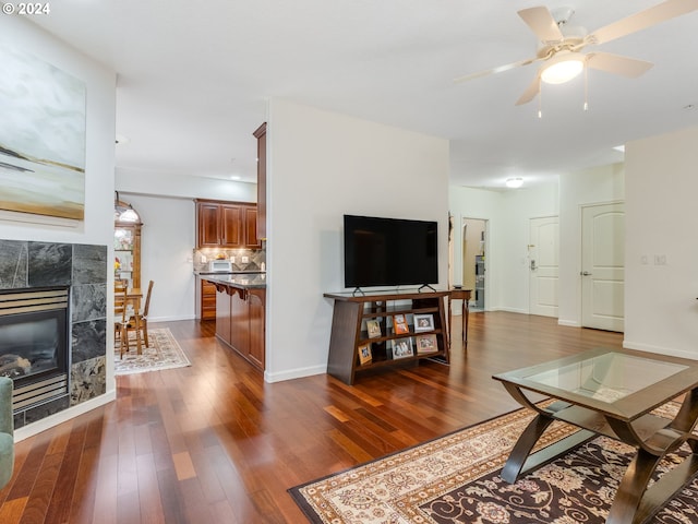 living room featuring a fireplace, dark hardwood / wood-style floors, and ceiling fan