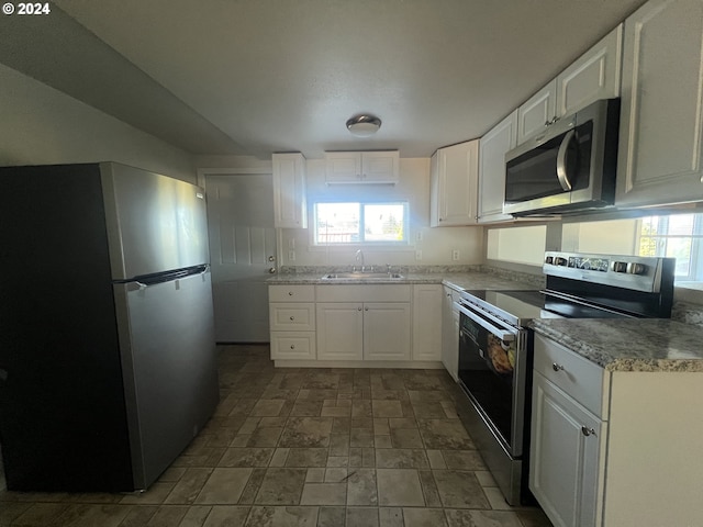 kitchen with appliances with stainless steel finishes, white cabinetry, and sink