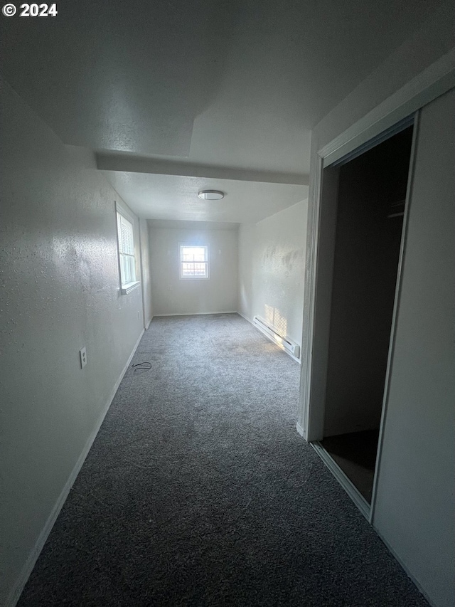 unfurnished room with carpet and a baseboard heating unit