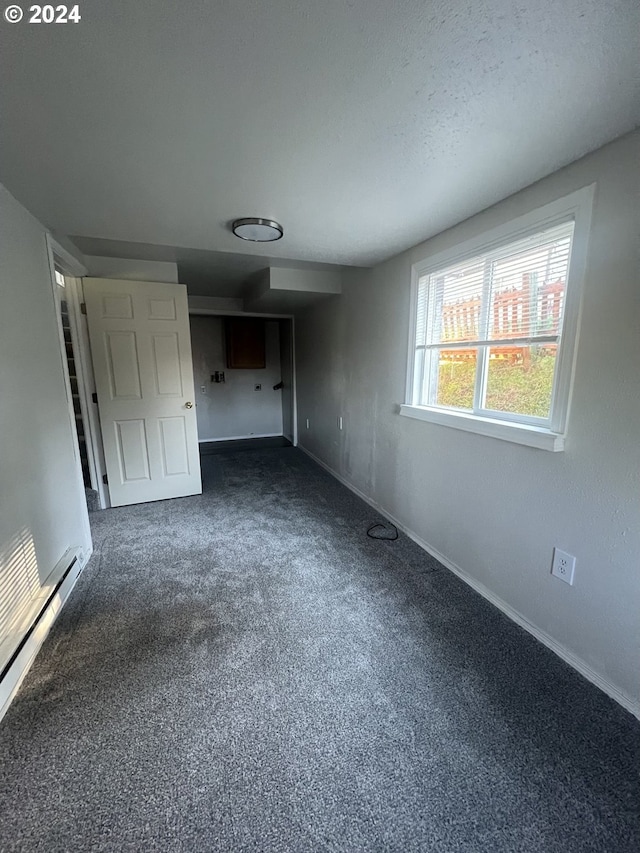 unfurnished bedroom featuring dark colored carpet and baseboard heating