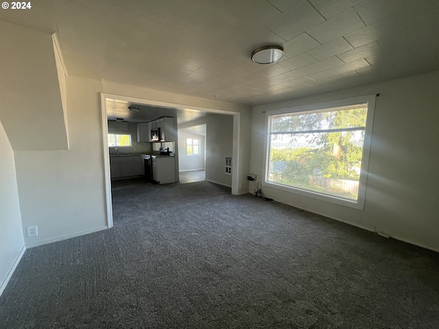 unfurnished living room featuring dark colored carpet and sink