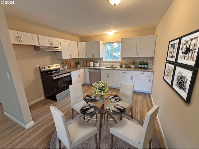 kitchen featuring light stone countertops, white cabinetry, sink, hardwood / wood-style floors, and appliances with stainless steel finishes