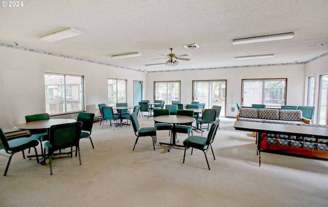 carpeted dining room with a textured ceiling and ceiling fan