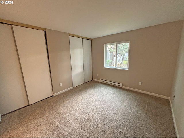 unfurnished bedroom featuring carpet flooring and a baseboard heating unit