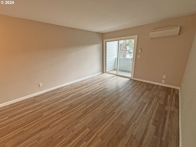 unfurnished room with a wall mounted AC and dark hardwood / wood-style flooring