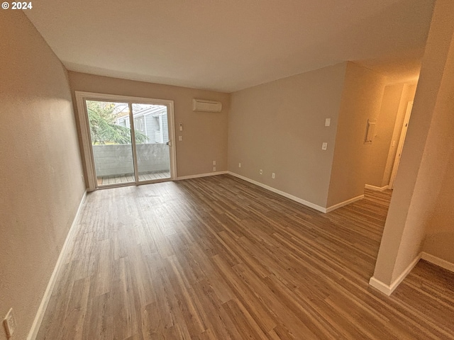 unfurnished room with a wall mounted AC and hardwood / wood-style flooring