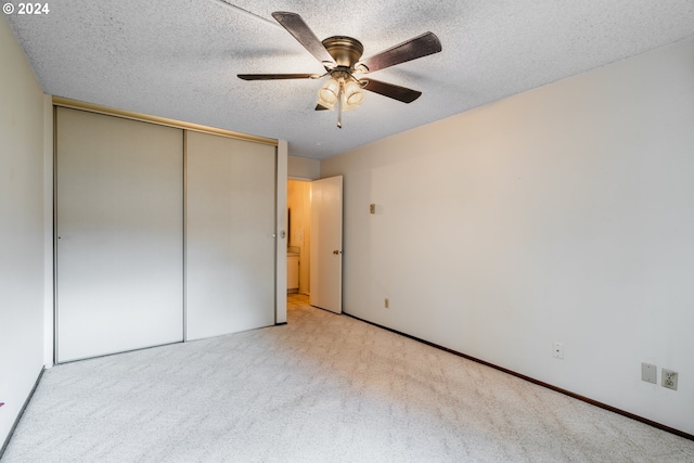 unfurnished bedroom with a closet, ceiling fan, a textured ceiling, and light colored carpet