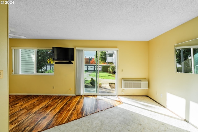 empty room with hardwood / wood-style flooring, a textured ceiling, and a wall mounted air conditioner